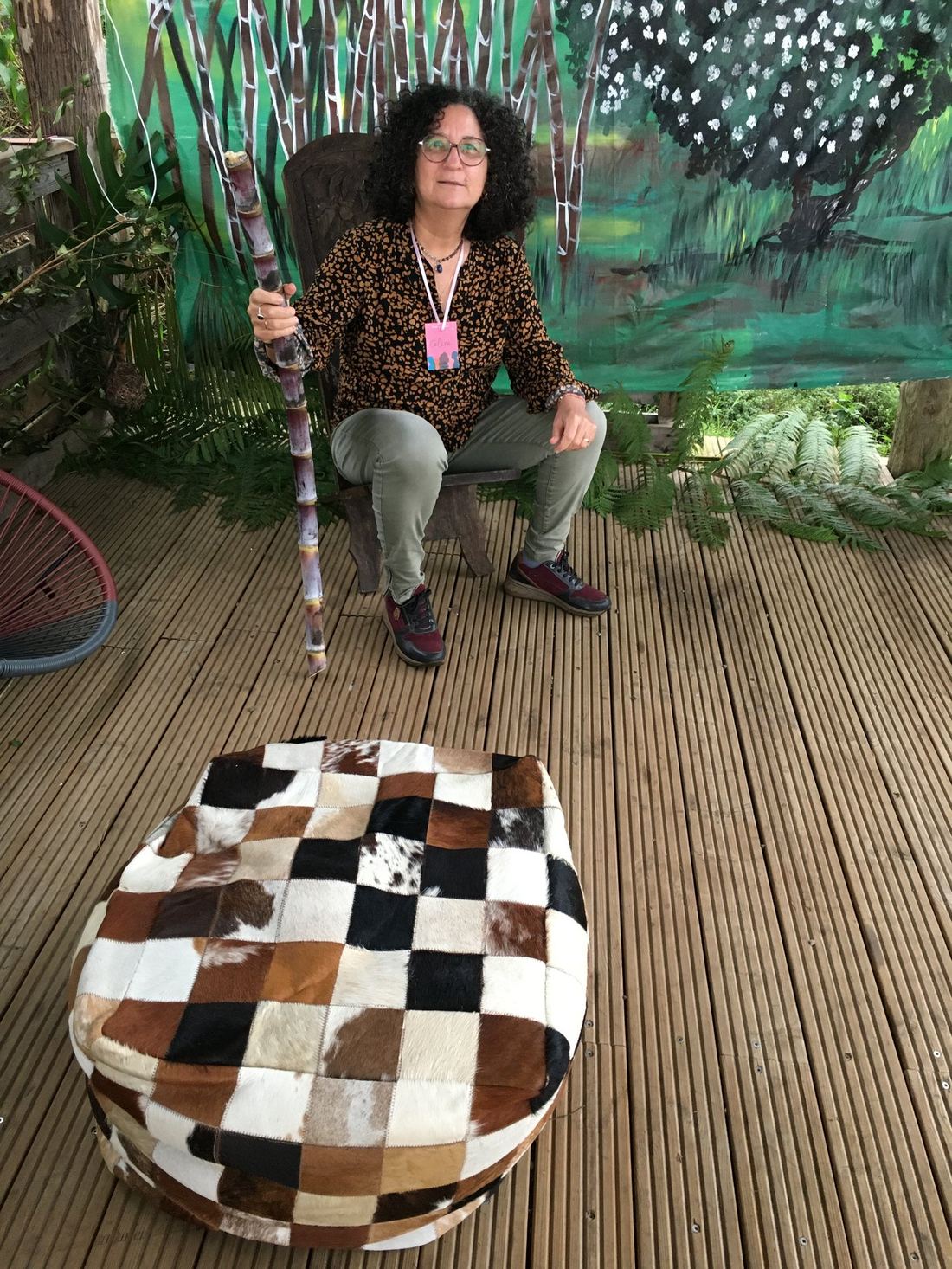 Une invitée assise avec une canne, près d'un pouf en peau de vache